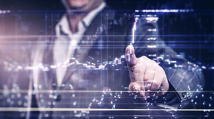 Man in a suit with finger on a touchscreen showing stock market trading graphs