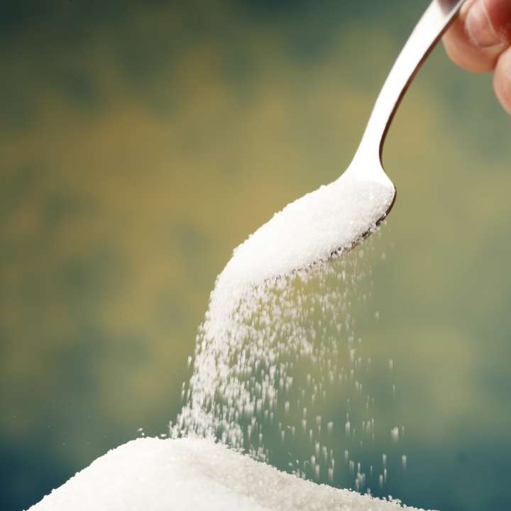 A spoonful of sugar falling into a pile of sugar