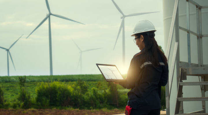 A woman engineer looking at a field with wind turbines