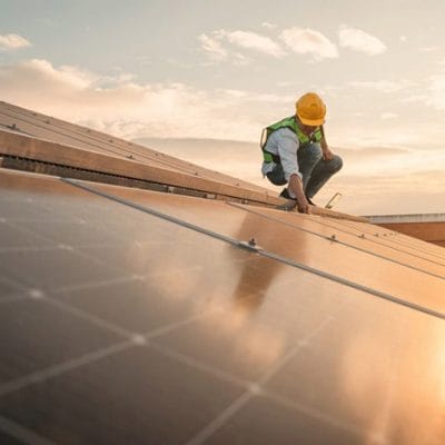 An engineer working on solar panels with a sun setting behind