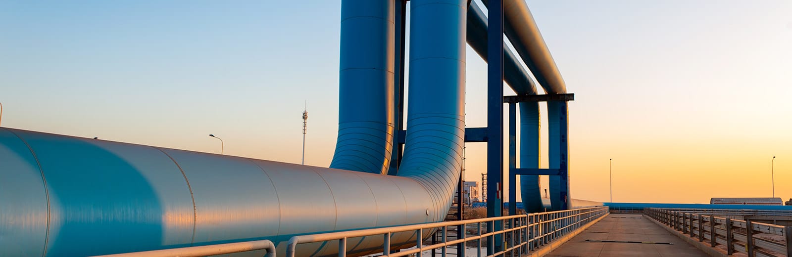 Natural gas pipelines going off into the distance with an orange glow of sunset