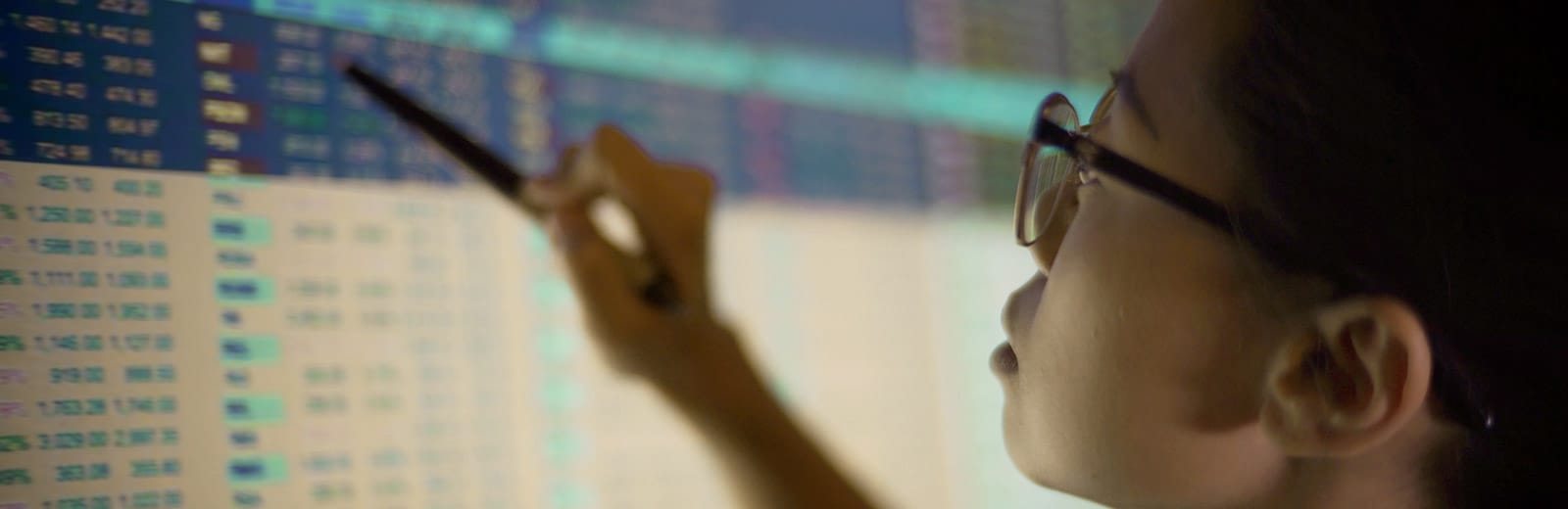 Stock market trader reviewing market data on a screen